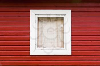 Red wooden wall with small window in white frame, typically Scandinavian living house architecture fragment