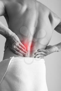 Young adult man with backache. Black and white stylized photo with red local pain spot
