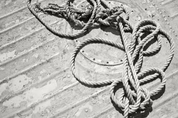Knotted mooring rope lying on grungy boat deck, old style black and white photo