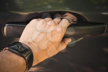 Male hand with wirst watch opens car door, closeup photo with selective focus