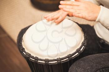 Drummer plays on small African drum, closeup photo with selective focus