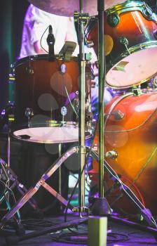 Drum set on a stage with colorful illumination, rock music photo background with tonal correction filter