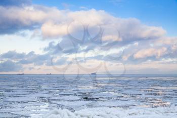 Winter coastal landscape with ice fragments and cloudy sky over horizon. Gulf of Finland, Russia