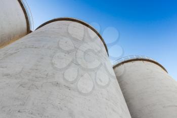 Abstract industrial architecture fragment, large tanks made of concrete for storage of bulk materials under blue sky
