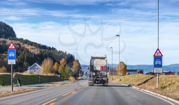 Empty truck without trailer goes on rural Norwegian road in autumn season, rear view