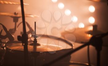 Warm toned musical photo, rock drum set  with cymbals and blurred stage lights on a background