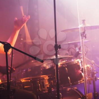 Vintage toned live music background, drummer plays with drumsticks on rock drum set. Closeup photo, soft selective focus