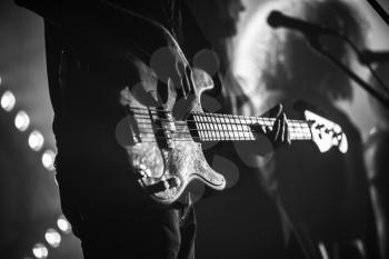 Close-up photo of electric bass guitar player, soft selective focus, live music theme, black and white