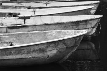 Old grungy rowboats moored in a row, black and white photo