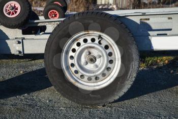 Closeup photo of trailer wheel on gray asphalt road