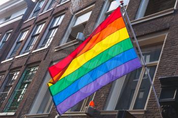 Rainbow flag representing LGBT pride mounted on house facade in Amsterdam, Netherlands