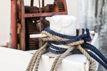 White bow bollard with ropes mounted on old ship deck