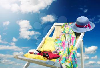 Hat and dress on deckchair against blue sky