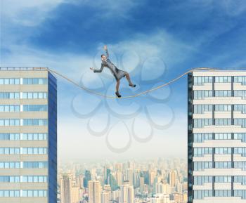 Businesswoman balancing on the rope between two high builgings against the city