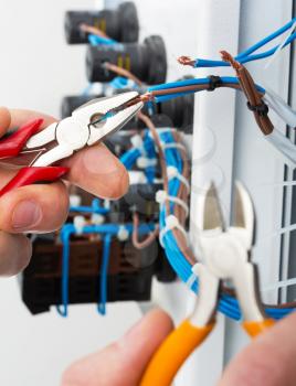 Hand of an electrician with tools at an electrical switchgear cabinet