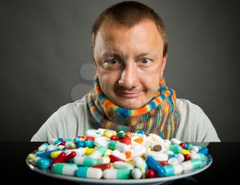 Surprised man looking on plate full of pills and capsules