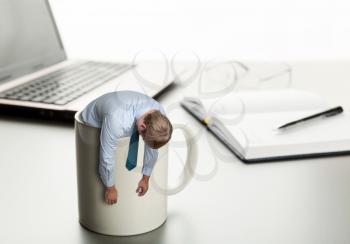 Exhausted man in cup on laptop background