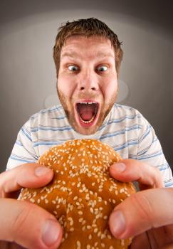 Portrait of expressive man eating juicy hamburger