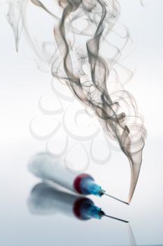 Syringe and smoke on white