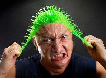 Mad man pulling on spiky green rubber hat
