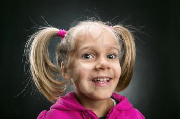 Smiling little girl in rose jacket on grey background