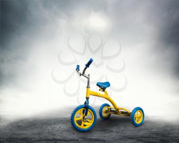 Yellow kid's bicycle stands on dark background