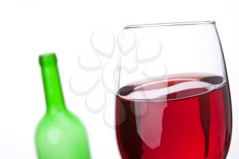 Close-up of red wine wineglass and empty bottle on background