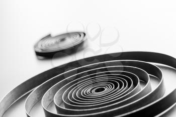 Closeup of two abstract metallic springs on grey background