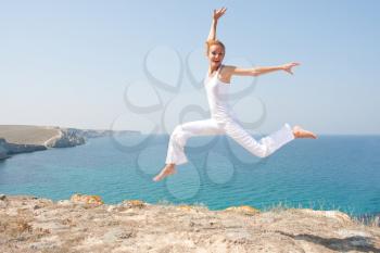 Jumping woman in white cloth against the sea