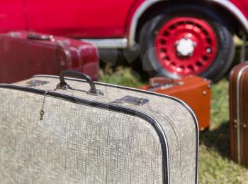 Old suitcases standing on the grass near a retro car