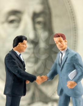 Miniature figurines of two successful handshaking businessmen
