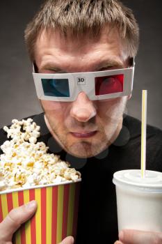 Funny man watching 3D movie, drinking soda and eating popcorn