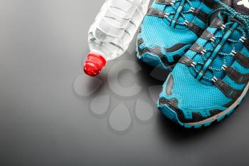 Sports runners and a bottle of water on grey background