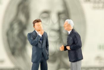 Miniature figurines of two discussing businessmen. Close-up view
