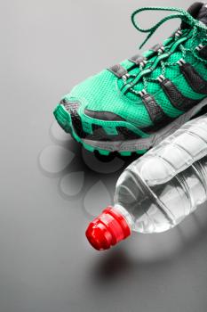 Sport shoe and a bottle of water on grey background
