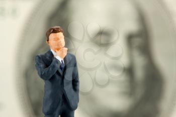 Miniature figurine of wisdom businessman with Franklin on background