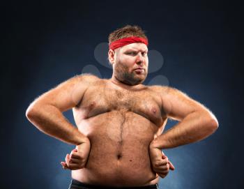 Fat man imitating muscular build studio shot