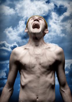 Portrait of despaired screaming man against dramatic sky