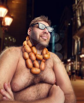 Cool man in glasses with sausages on his neck sits in the evening city