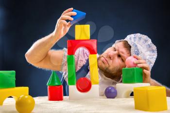 Man weared as baby playing with toy bricks