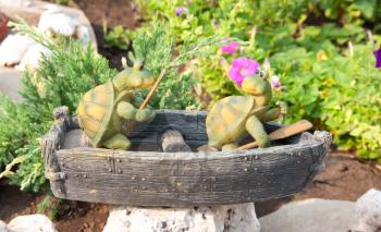 Garden statue. Two funny frogs on the boat