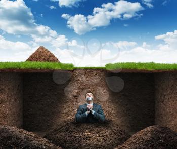 Businessman sits as hostage underground in the soil