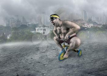 Adult naked man cycling in the foggy street on child's bicycle