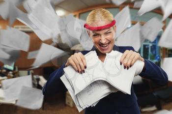 Angry businesswoman tearing papers in pieces in the office