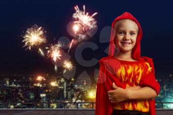 Little girl in masquerade costume in the evening street over the firework