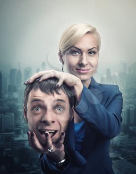 Happy businesswoman with man's head in her hand