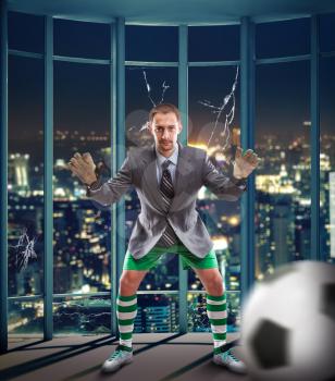 Businessman like a goalkeeper plays football in the office