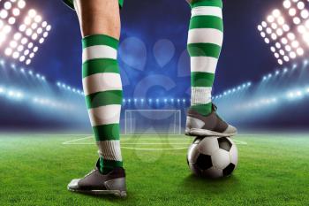 Football player legs with a ball standing on the football ground