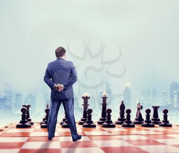 Businessman standing in front of the black team on the chess board 