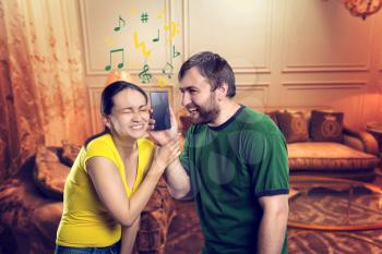 Young couple listening to music using smartphone in the room